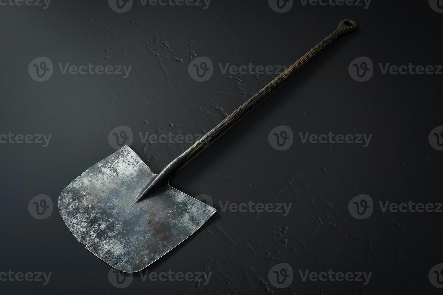 Rustic shovel resting on a textured dark surface photo