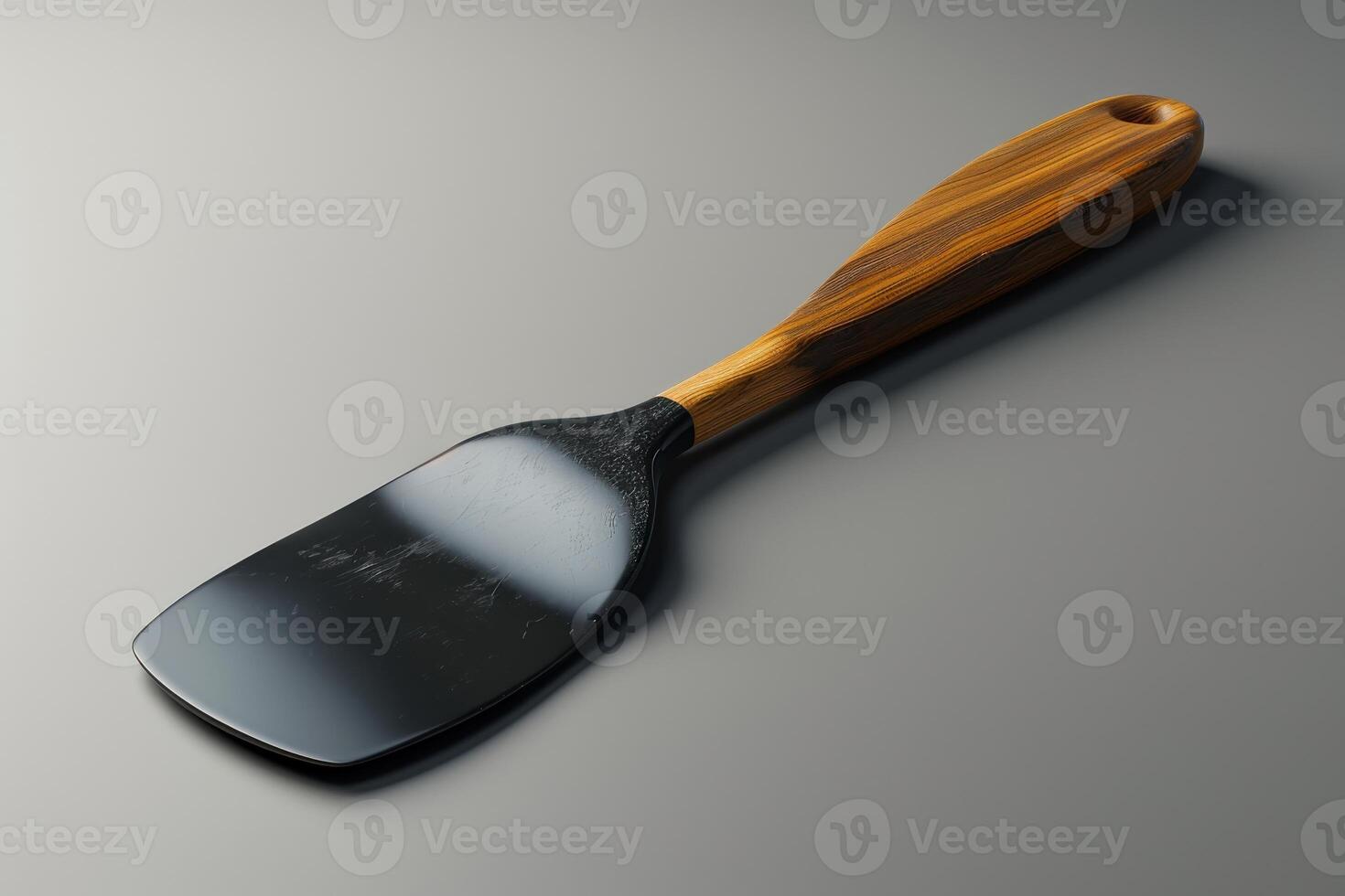 A wooden handle spatula resting on a smooth gray surface in natural light photo