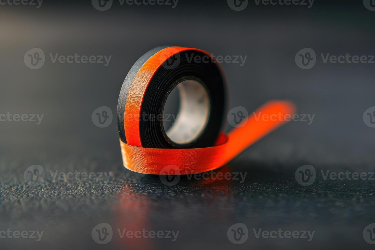 Close-up of a roll of black and orange tape on a textured surface in a well-lit environment photo