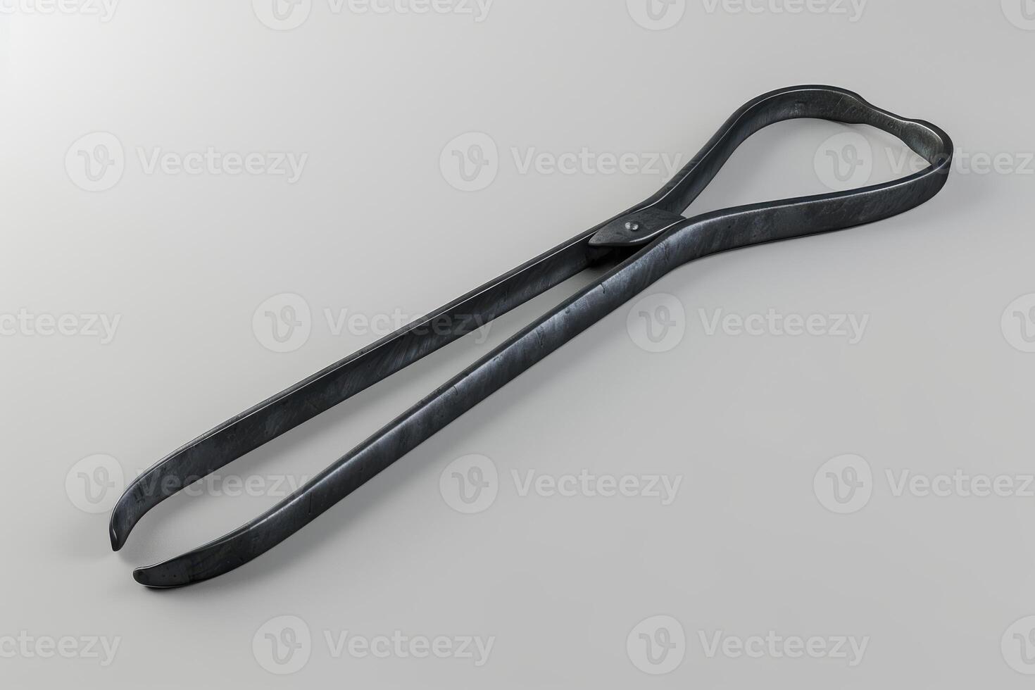 Metal tongs placed on a gray surface showcasing their sleek design and functional shape photo