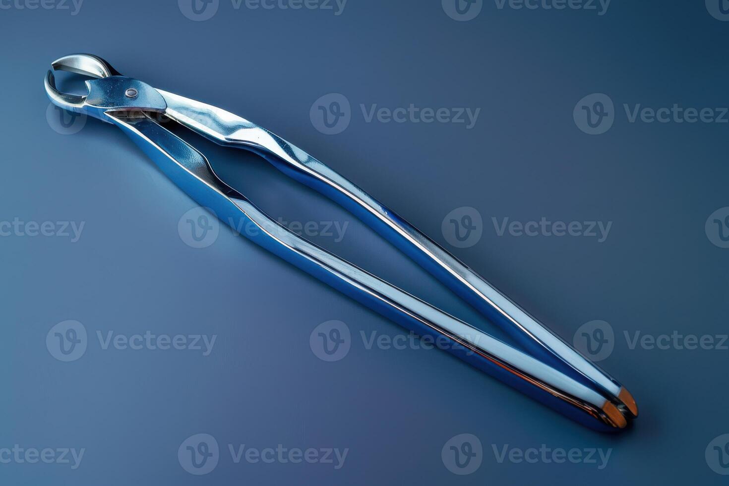 Sleek stainless steel tongs resting on a blue surface in a well-lit kitchen environment photo