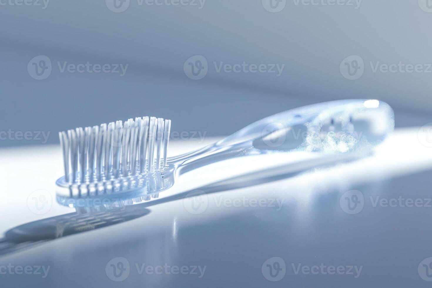 Transparent toothbrush resting on a reflective surface with soft lighting photo