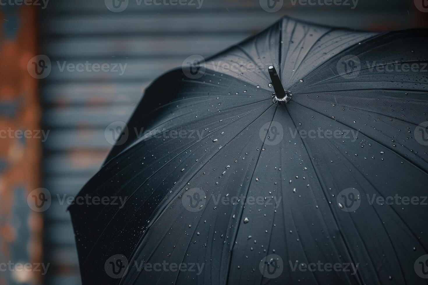 Black umbrella with raindrops standing against a weathered background on a rainy day photo