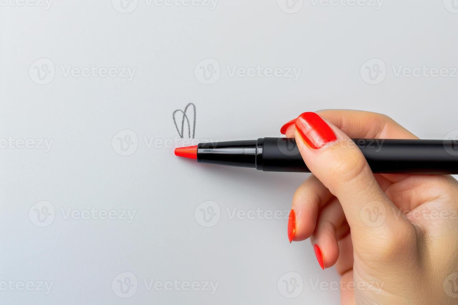Hand holding a red marker drawing a heart on a blank sheet of paper photo