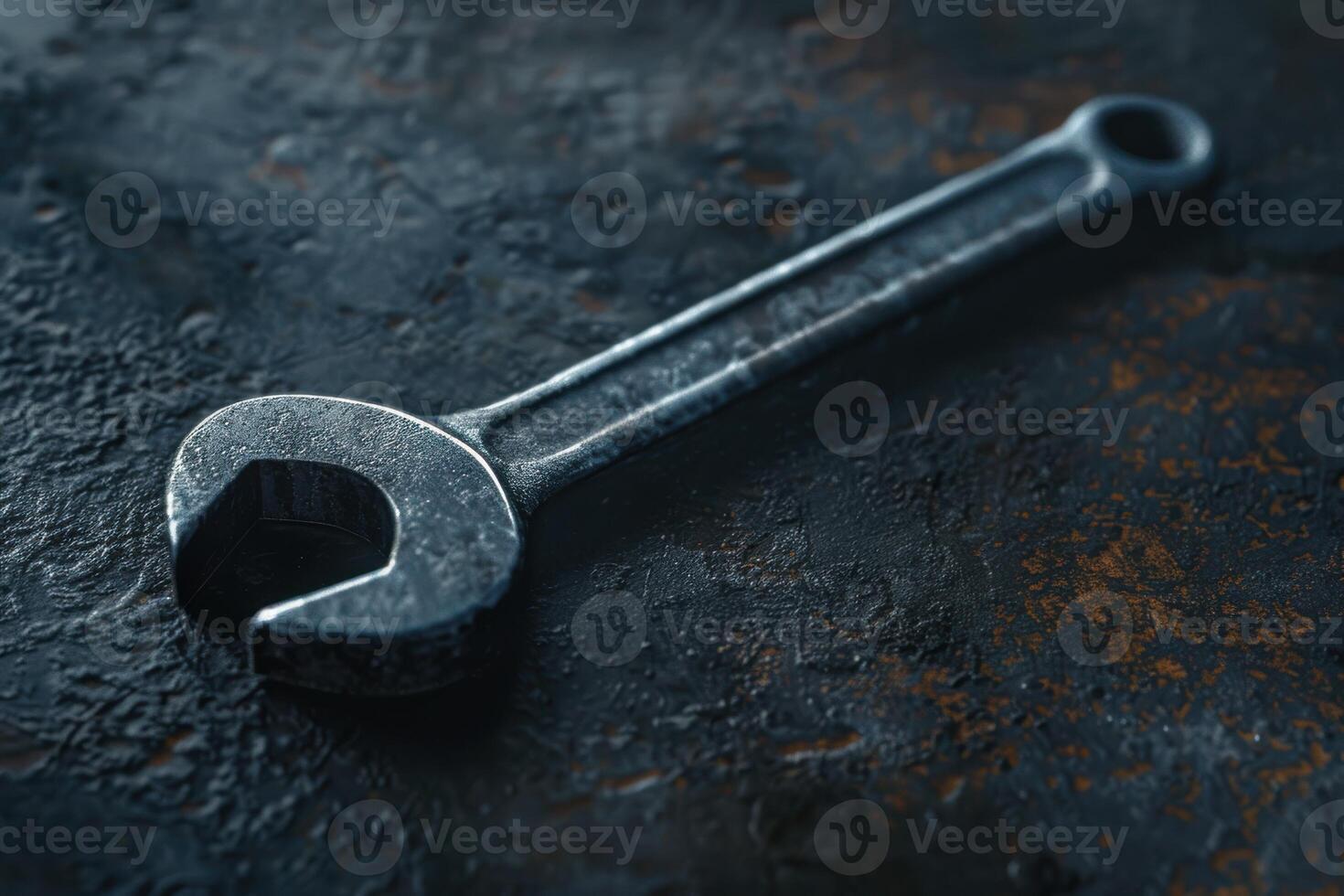 A close-up view of a metallic adjustable wrench resting on a textured surface in a workshop setting photo