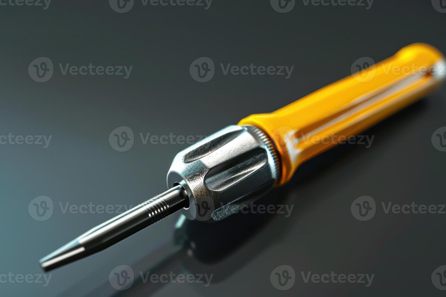 Close-up of a yellow-handled screwdriver resting on a glossy black surface photo