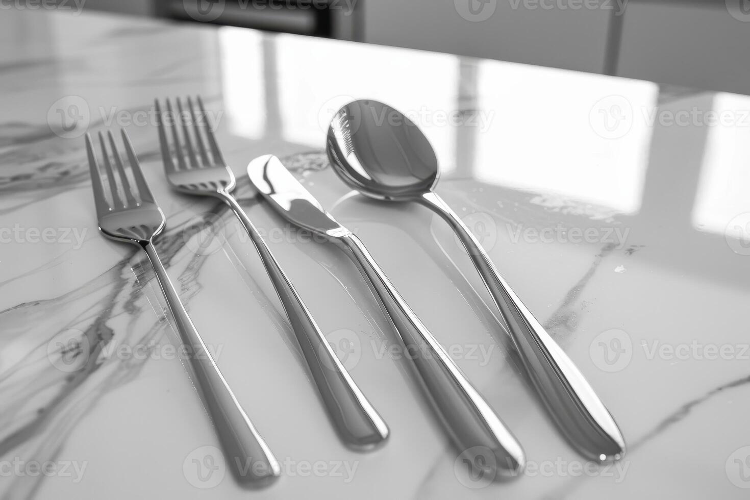Set of elegant silver cutlery arranged neatly on a marble countertop in a bright kitchen photo