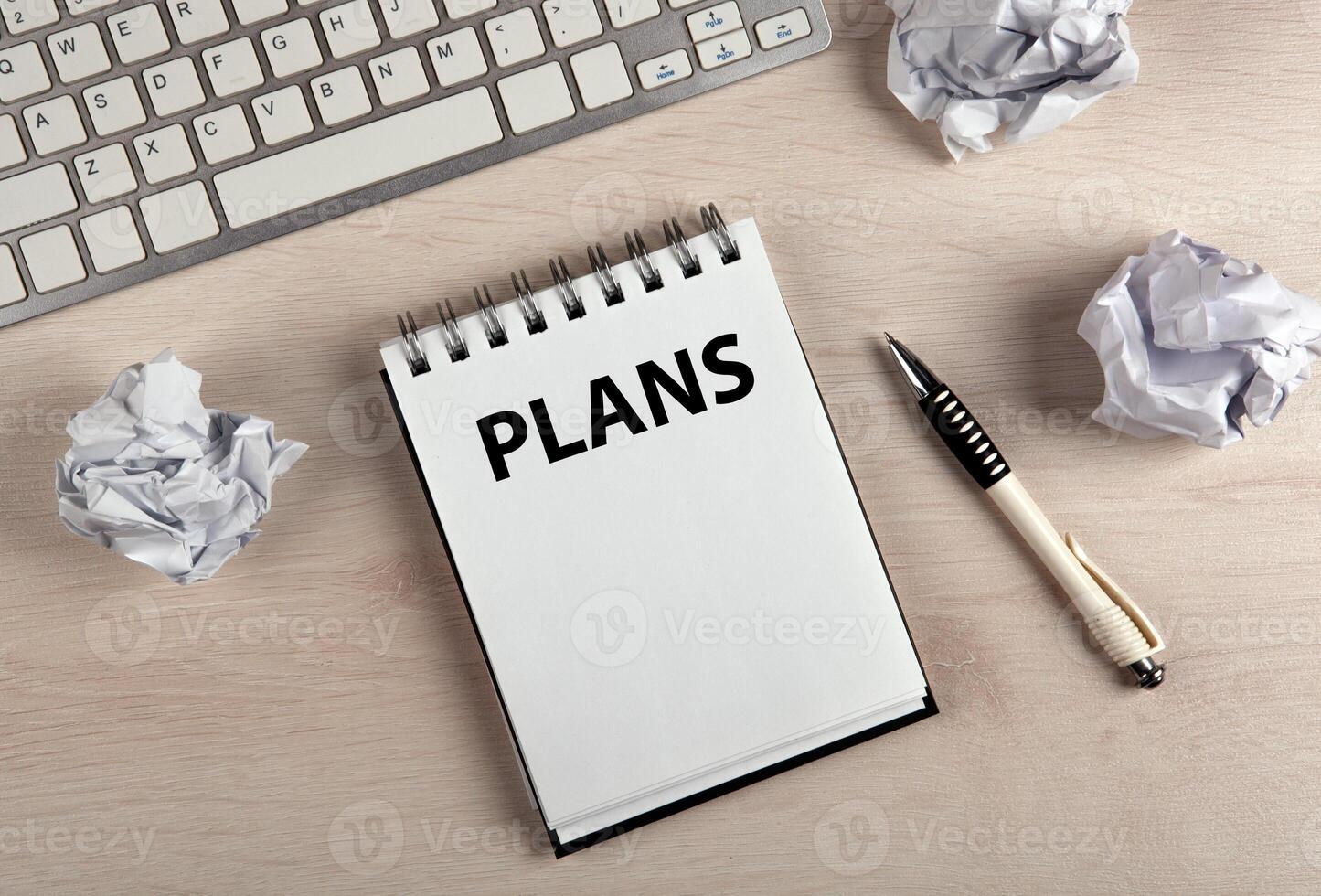 work table, a notebook with title plans a pen and crumpled paper photo