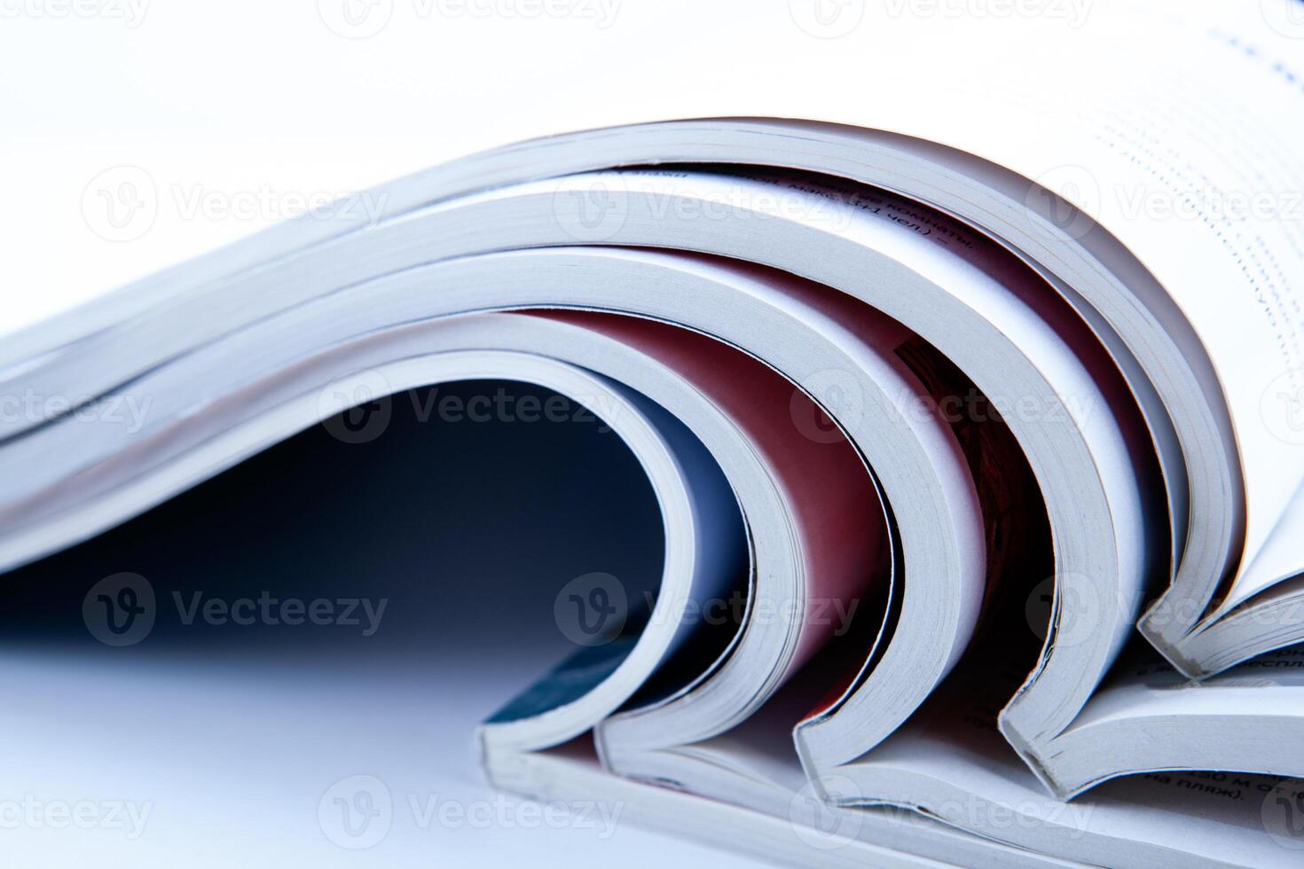 stack of open glossy magazines on white background photo