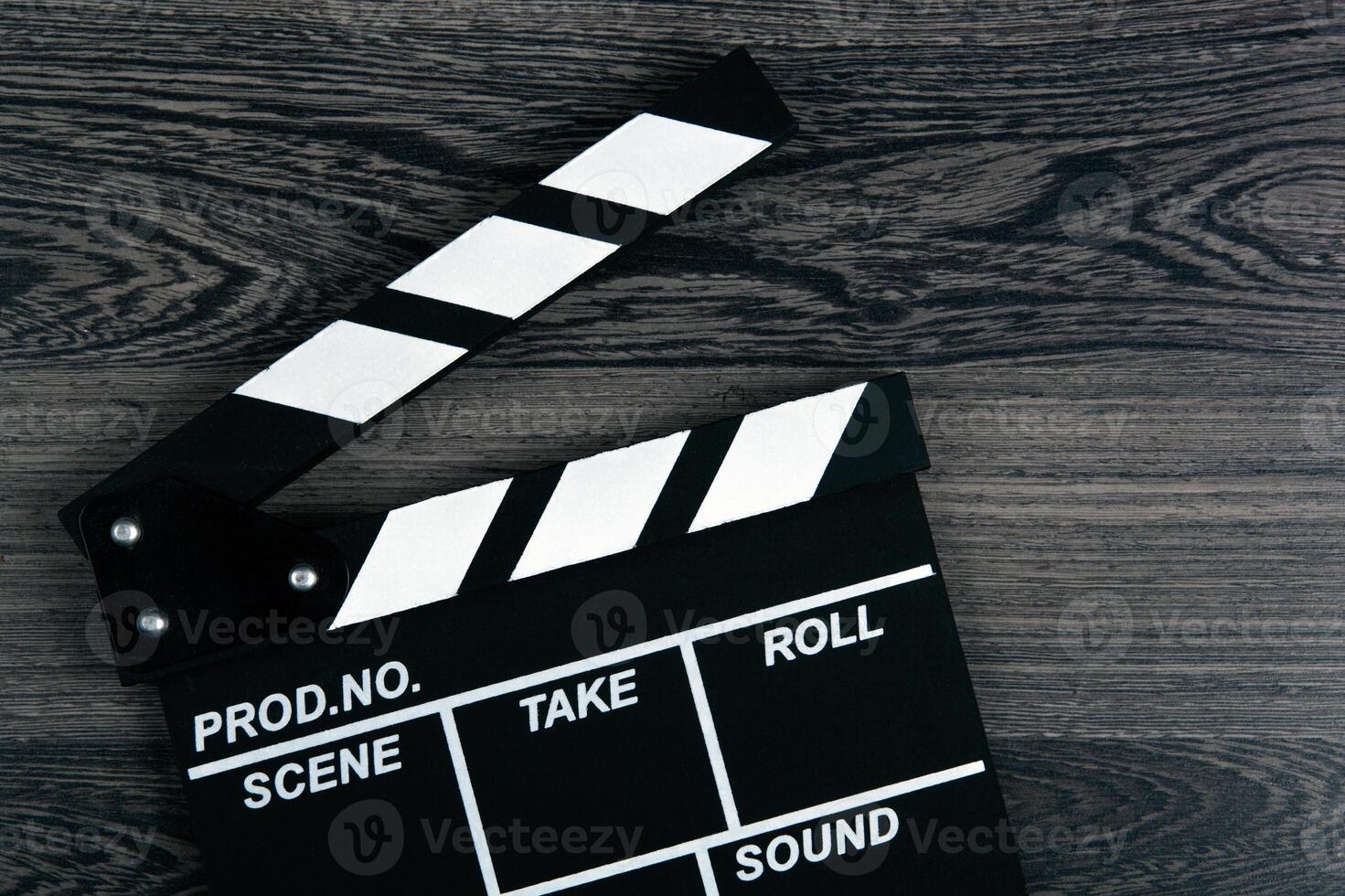 black movie clapper with white inscriptions on a wooden table photo