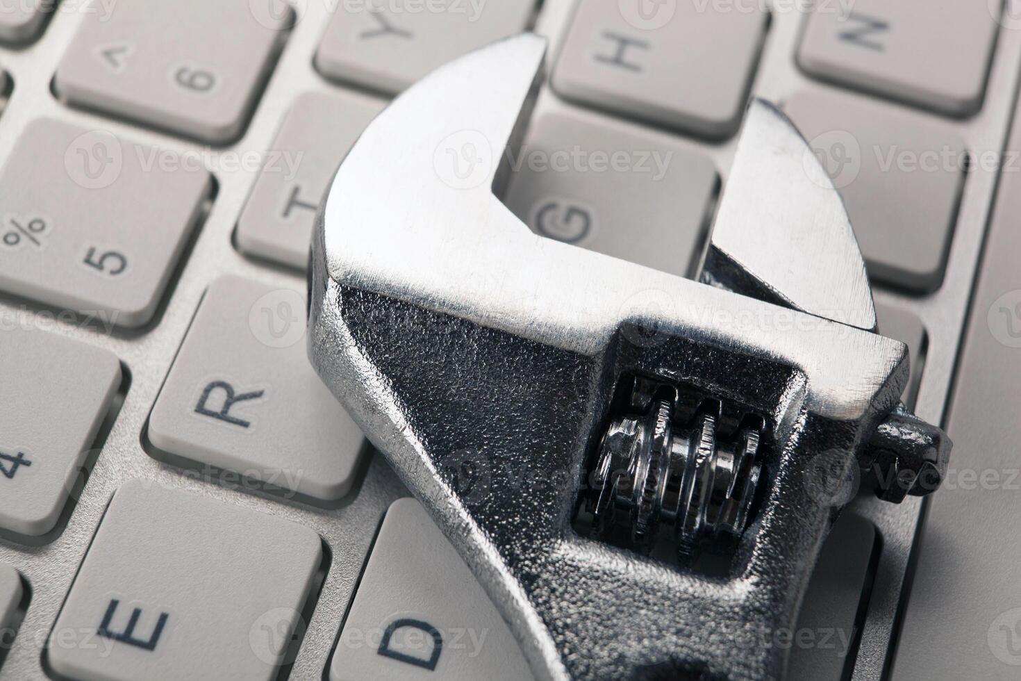big adjustable wrench and a computer keyboard close up photo