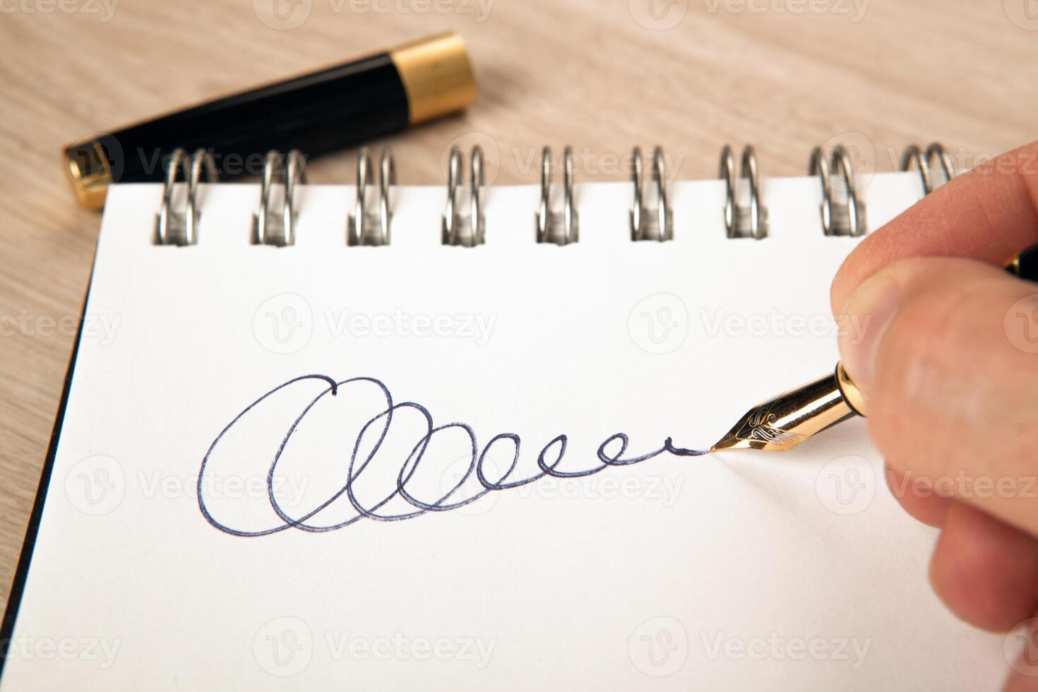 golden fountain pen in the hand and a signature on the paper photo
