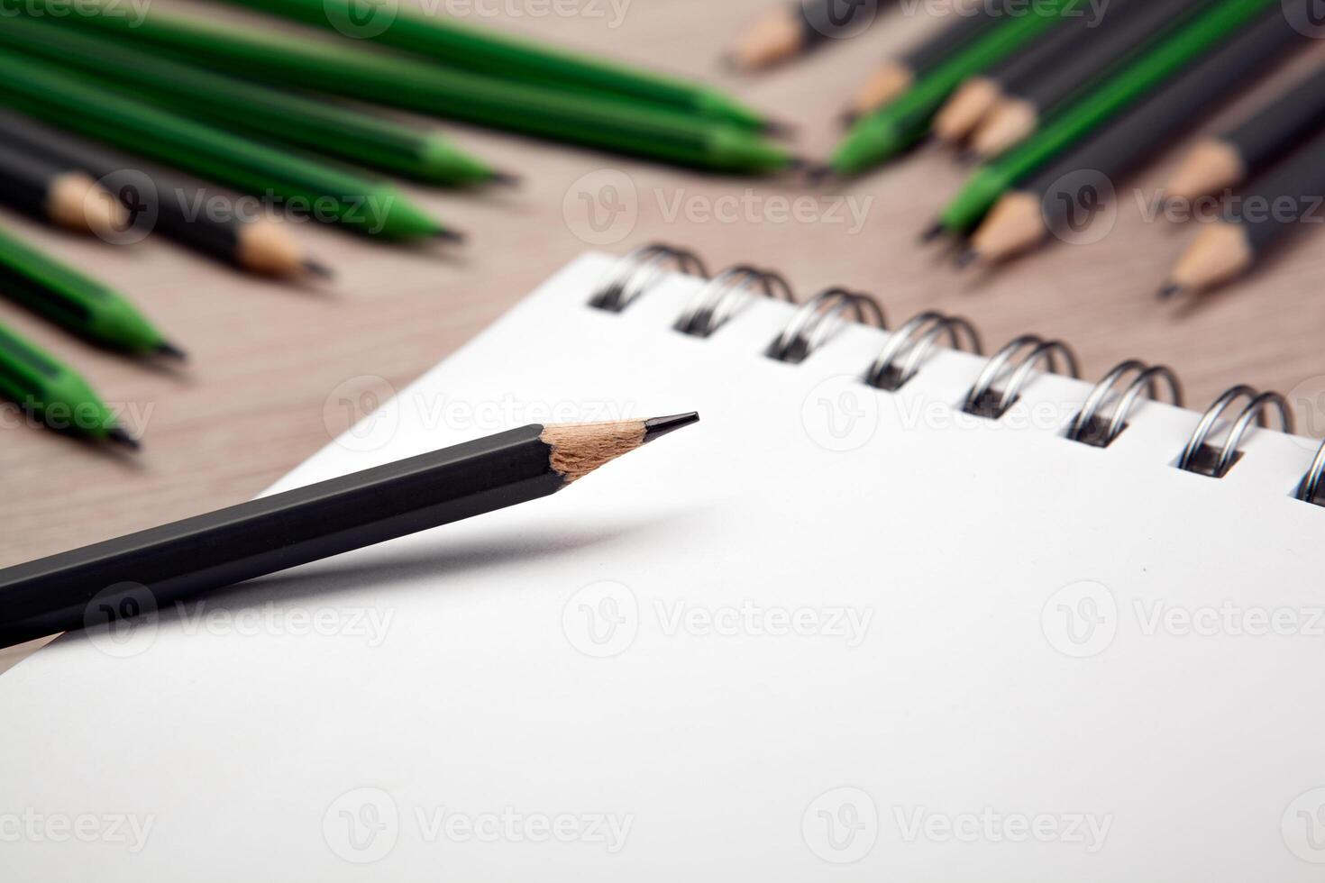 open notebook with the one simple pencil and the rest of the pencils on the background photo