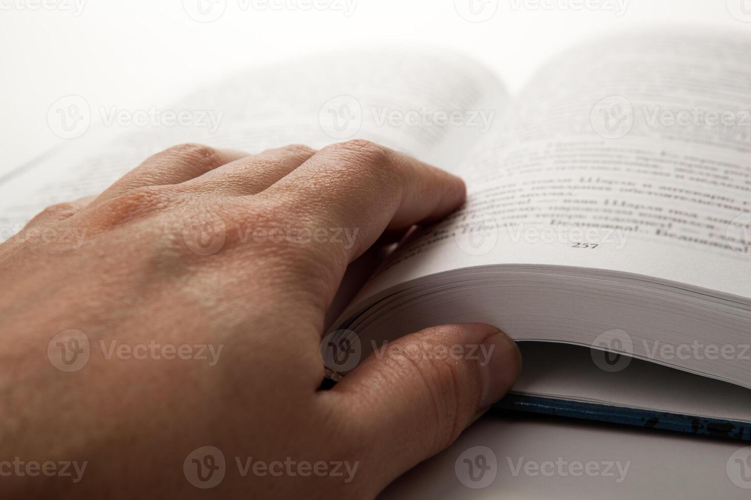 man's hand on an open book with white pages photo