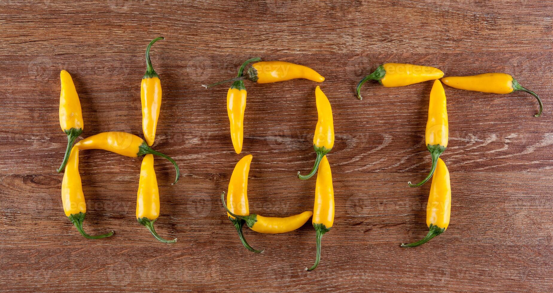 fresh chilli pepper on a wooden background in the form of text hot photo