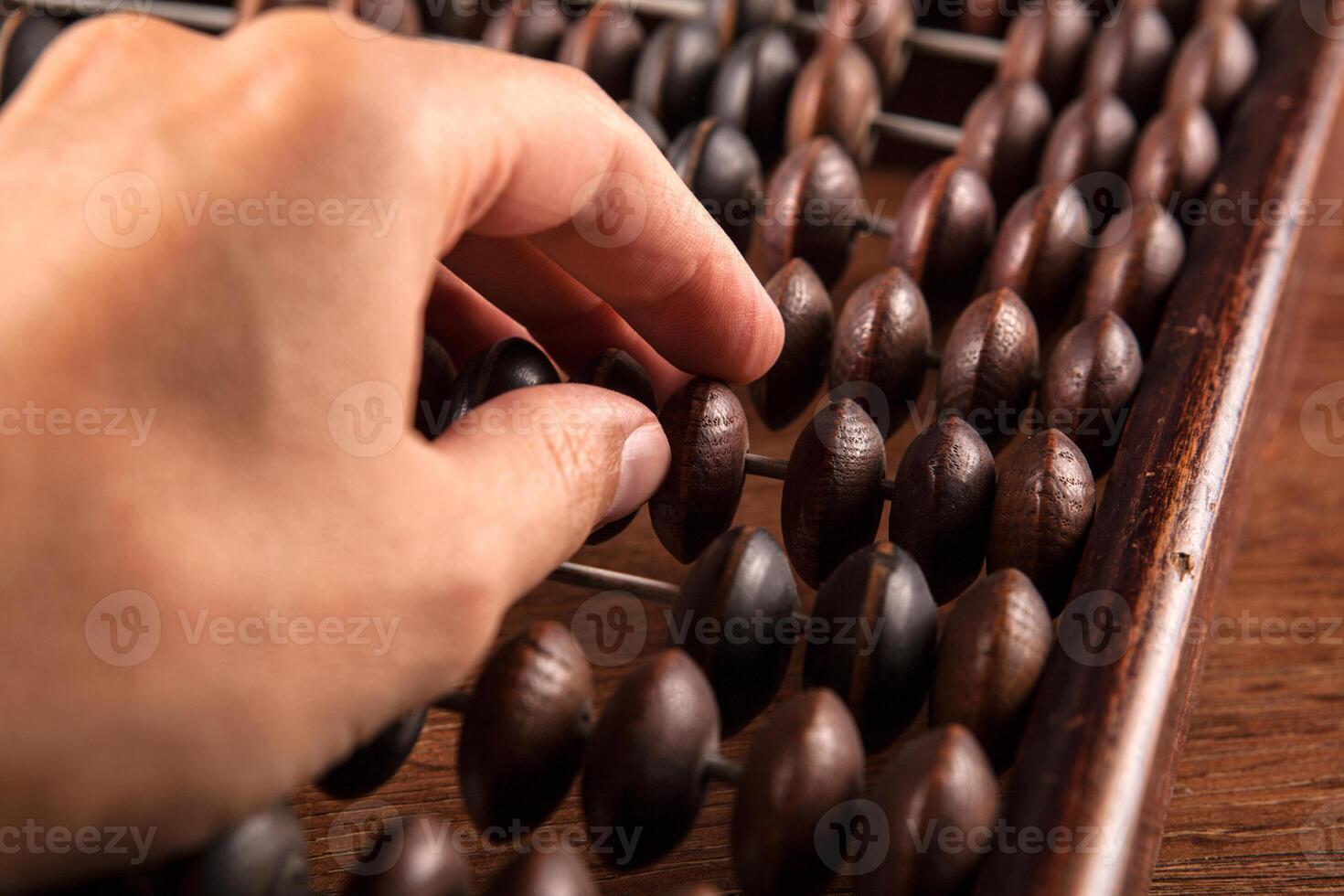 antique abacus on a wooden table and the hand of man close up photo