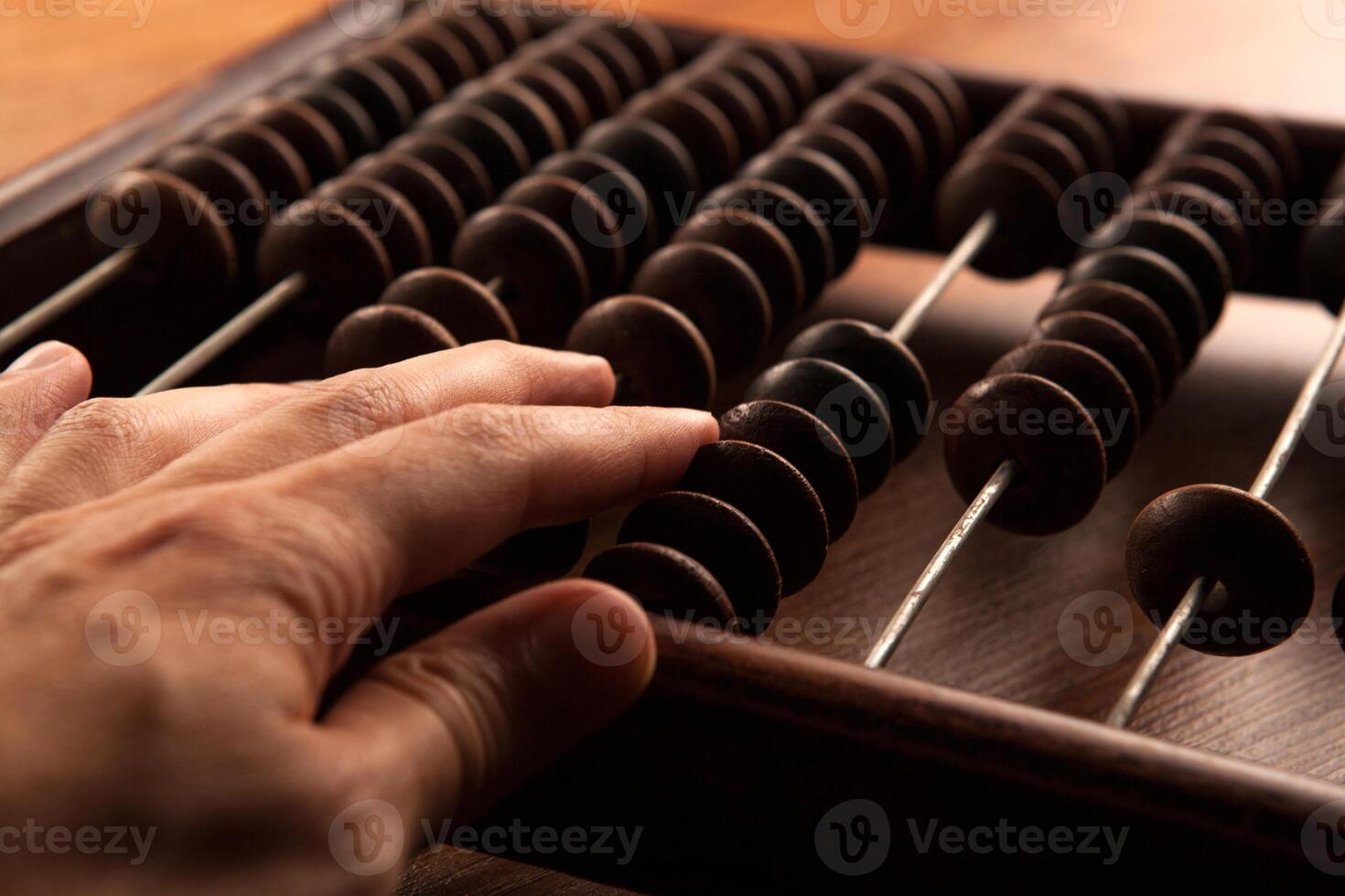antique abacus on a wooden table and the hand of man close up photo