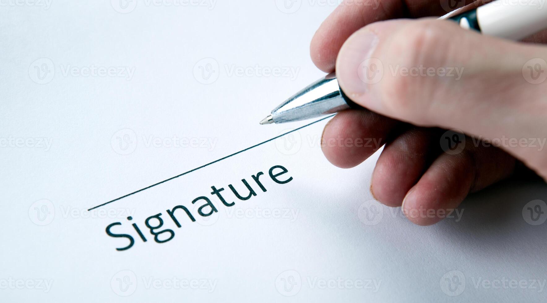 One document with a place for a signature and a hand of a man with a pen photo