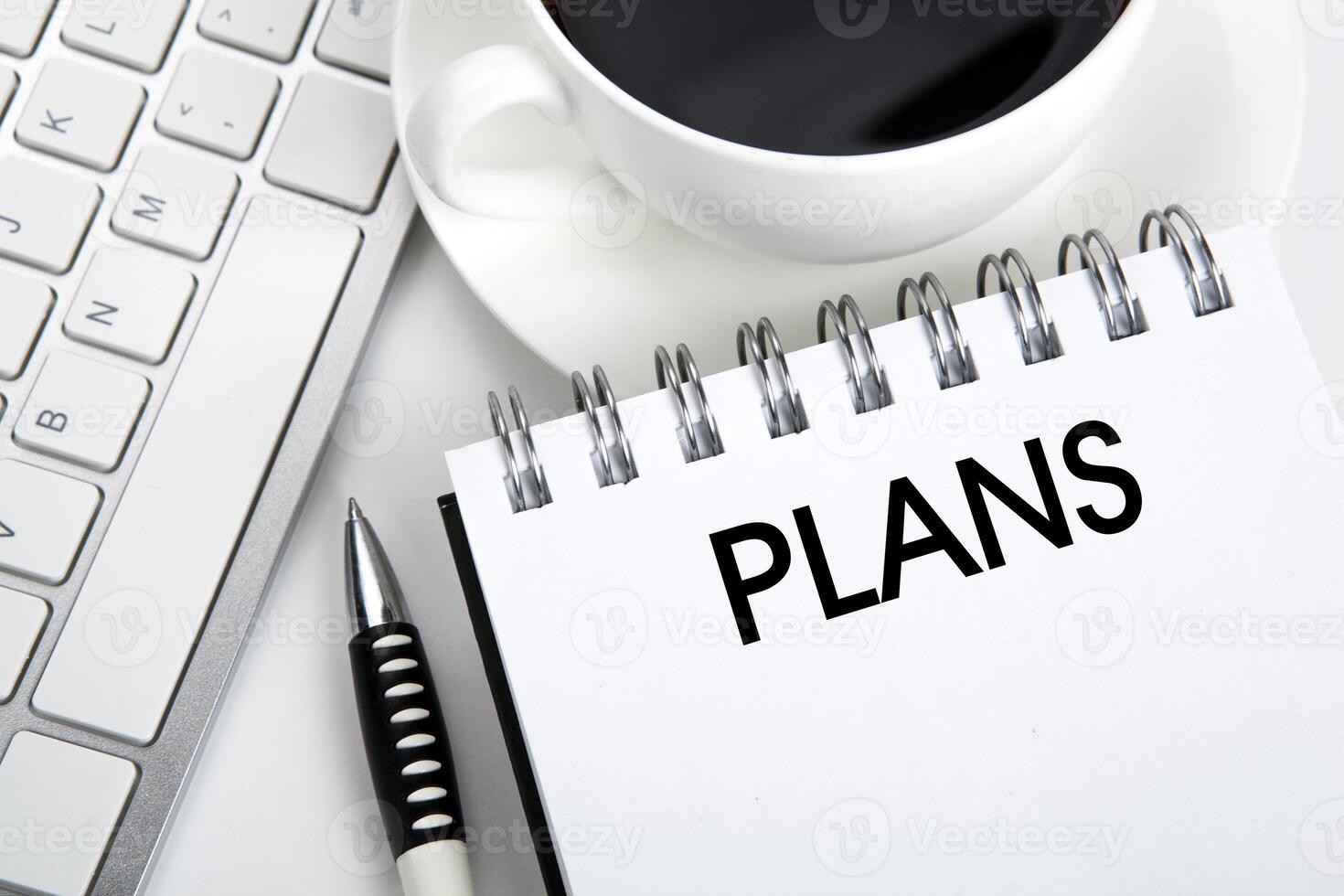 business still life of a notebook with an inscription plans and keyboard on the desktop photo
