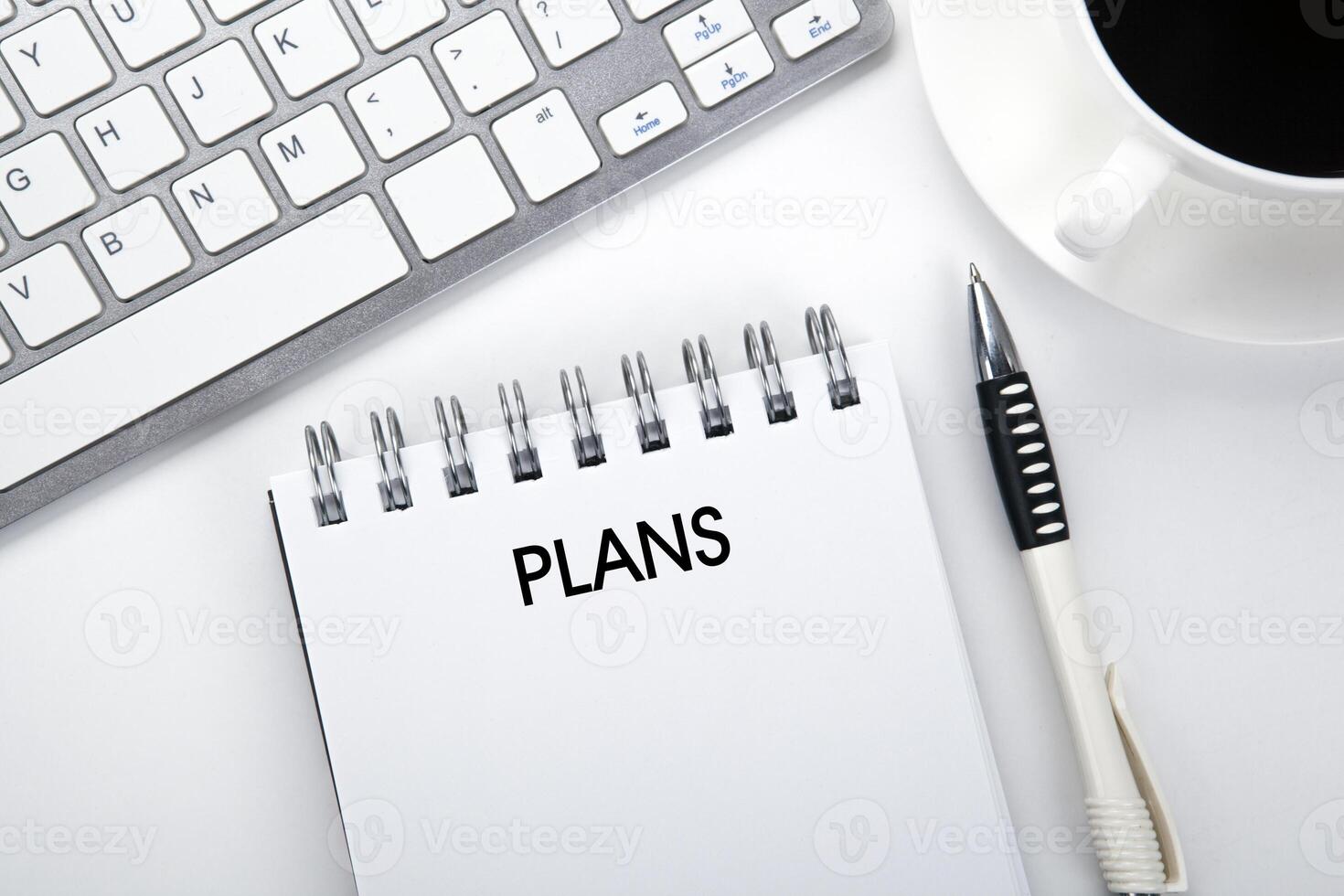 business still life of a notebook with an inscription plans and keyboard on the desktop photo
