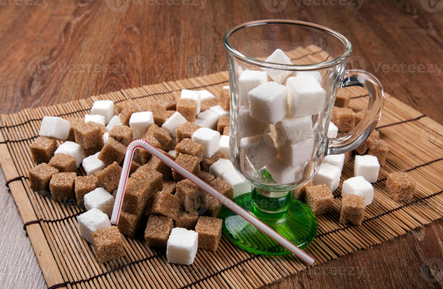 still life of cubes of white and brown sugar in a glass and on a table photo