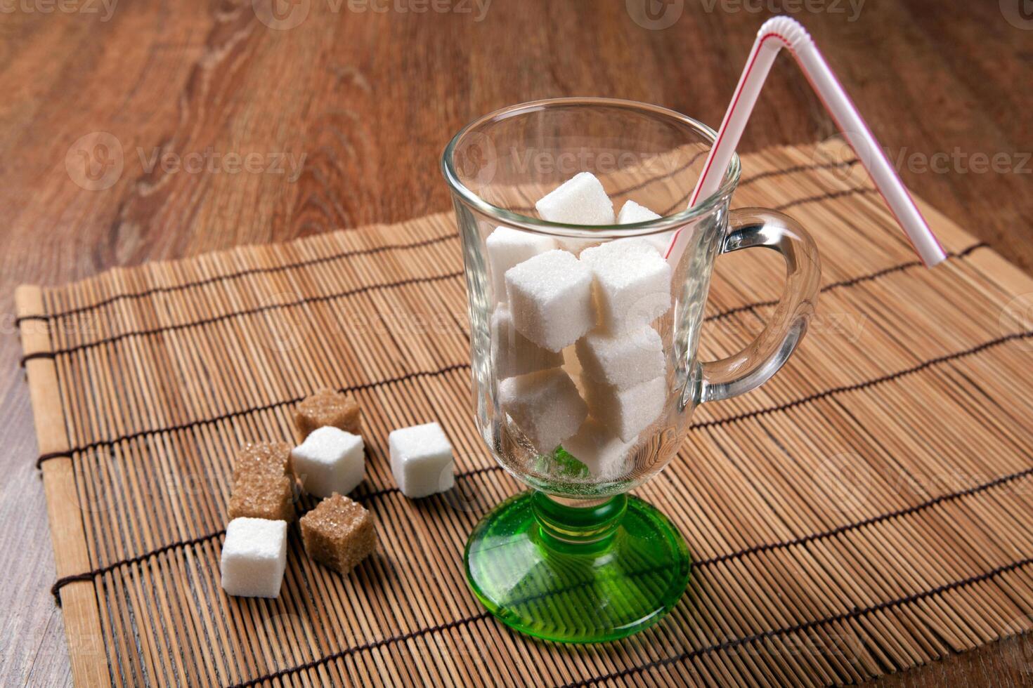 still life of cubes of white and brown sugar in a glass and on a table photo