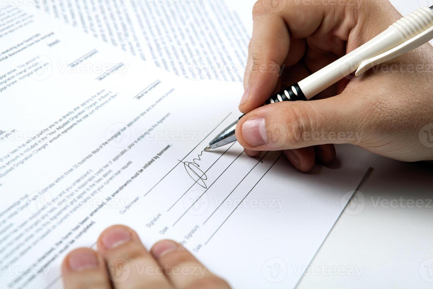 the man's hand signs the document and the signature photo