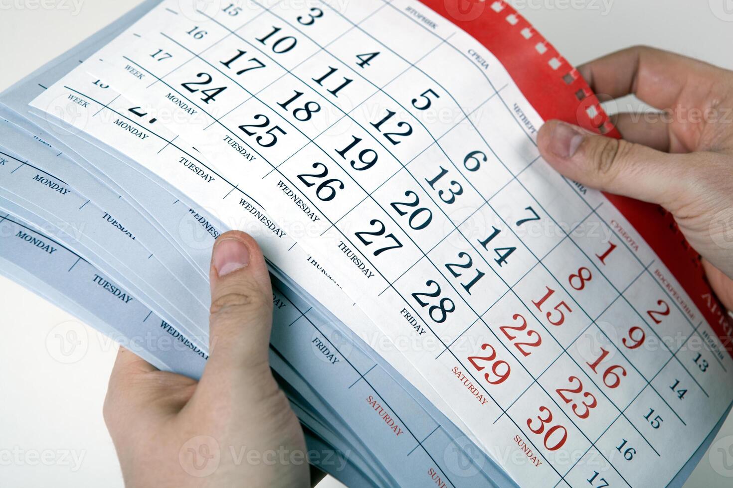 hands of men hold the sheets of the calendar photo