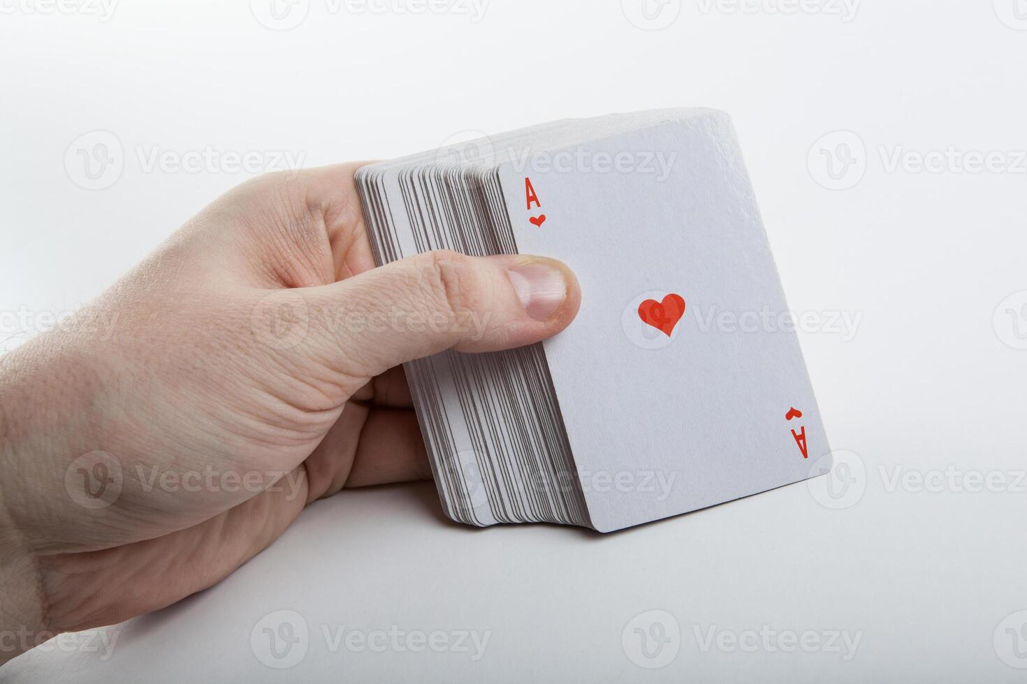 Human hand holding the ace of hearts and a deck of cards photo