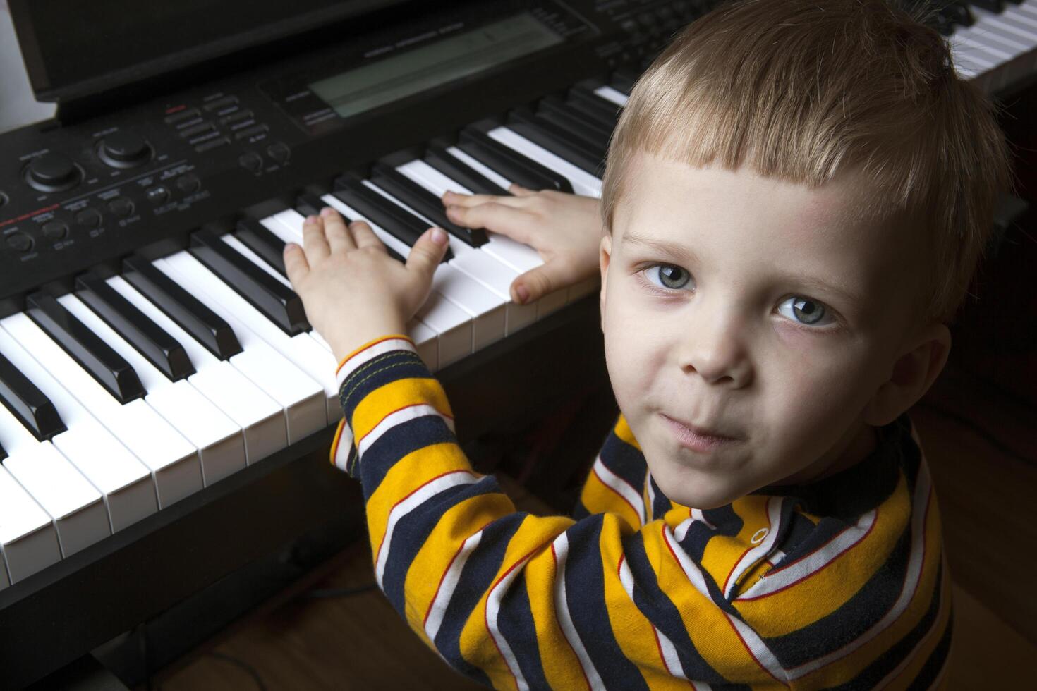 talented little boy sitting at the piano photo