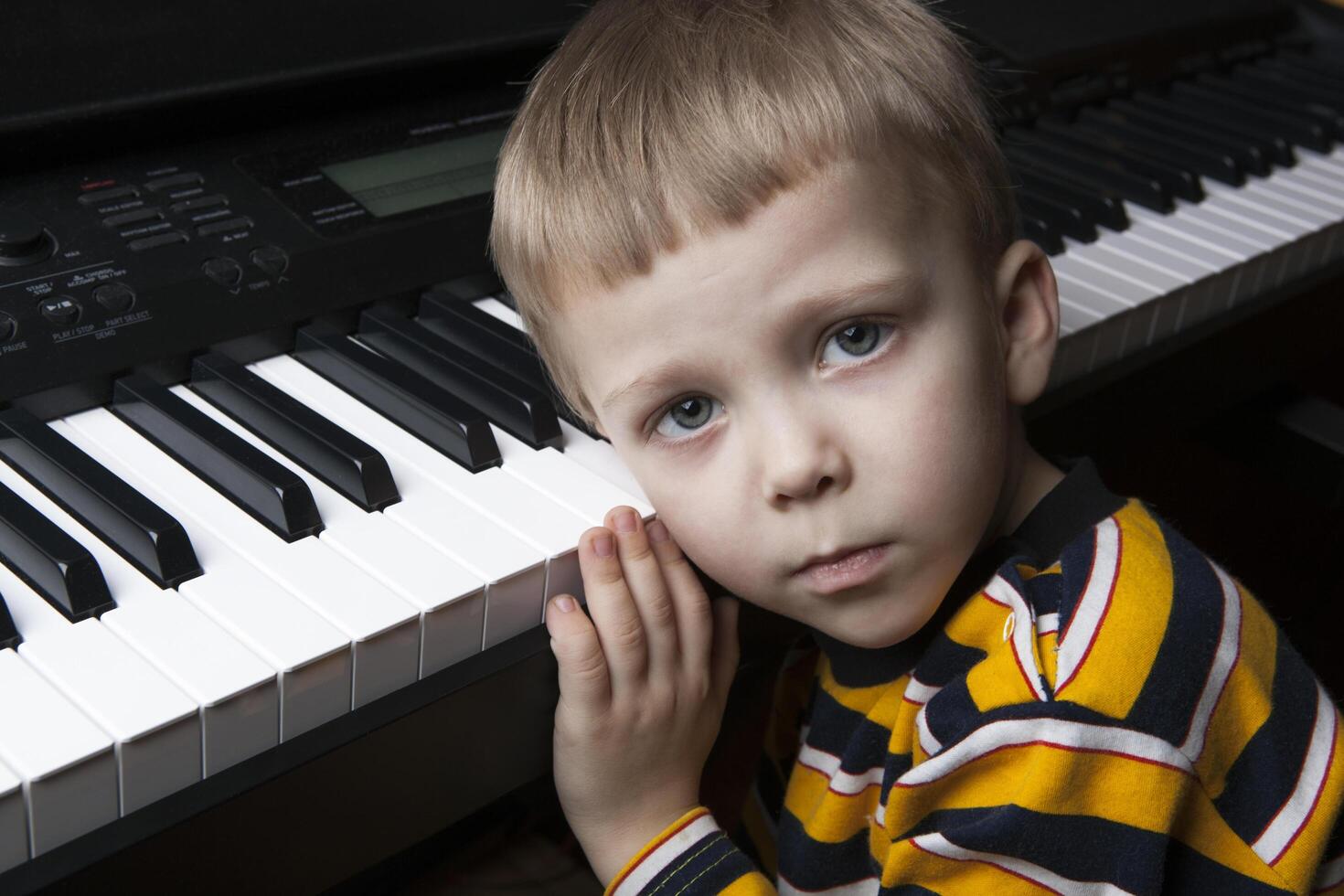 dreaming little boy sitting at the piano photo