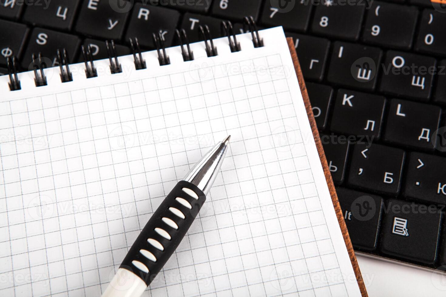 pen on a notebook into a cell and keyboard photo