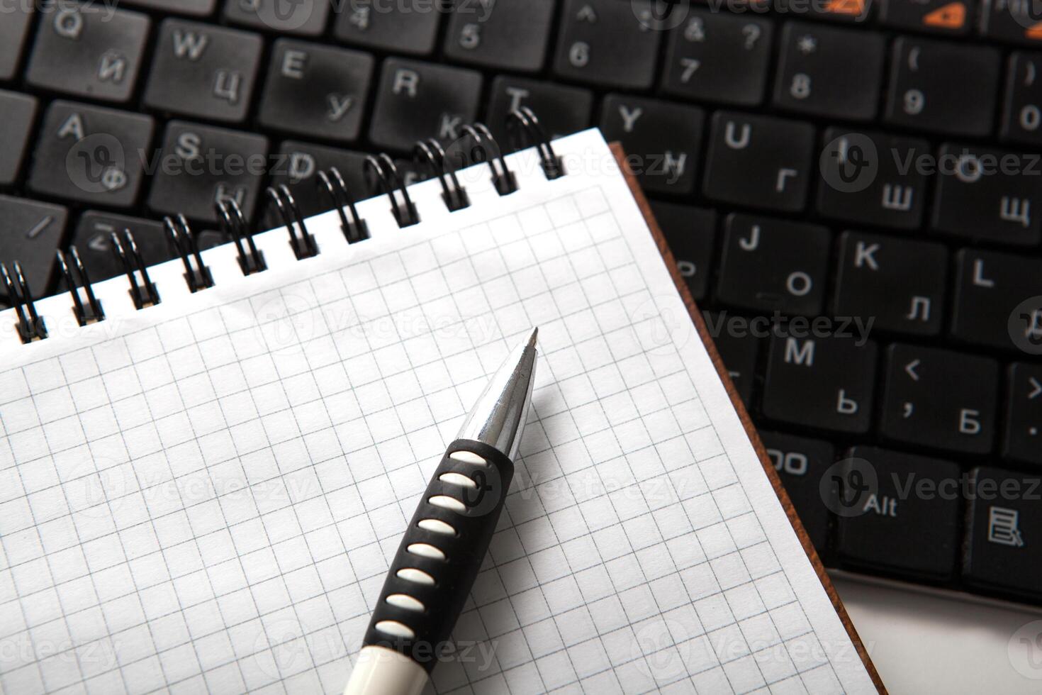 pen on a notebook into a cell and keyboard photo