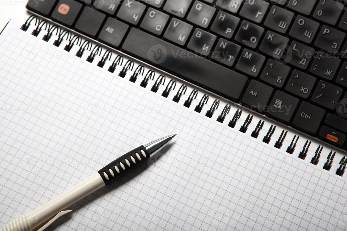 pen on a notebook into a cell and keyboard photo