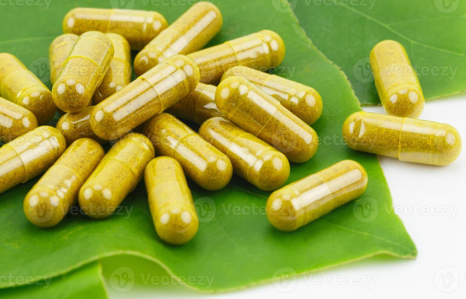 Turmeric Powder in Transparency Hard Gelatin Capsules with Green Natural Leaves on White Background. photo