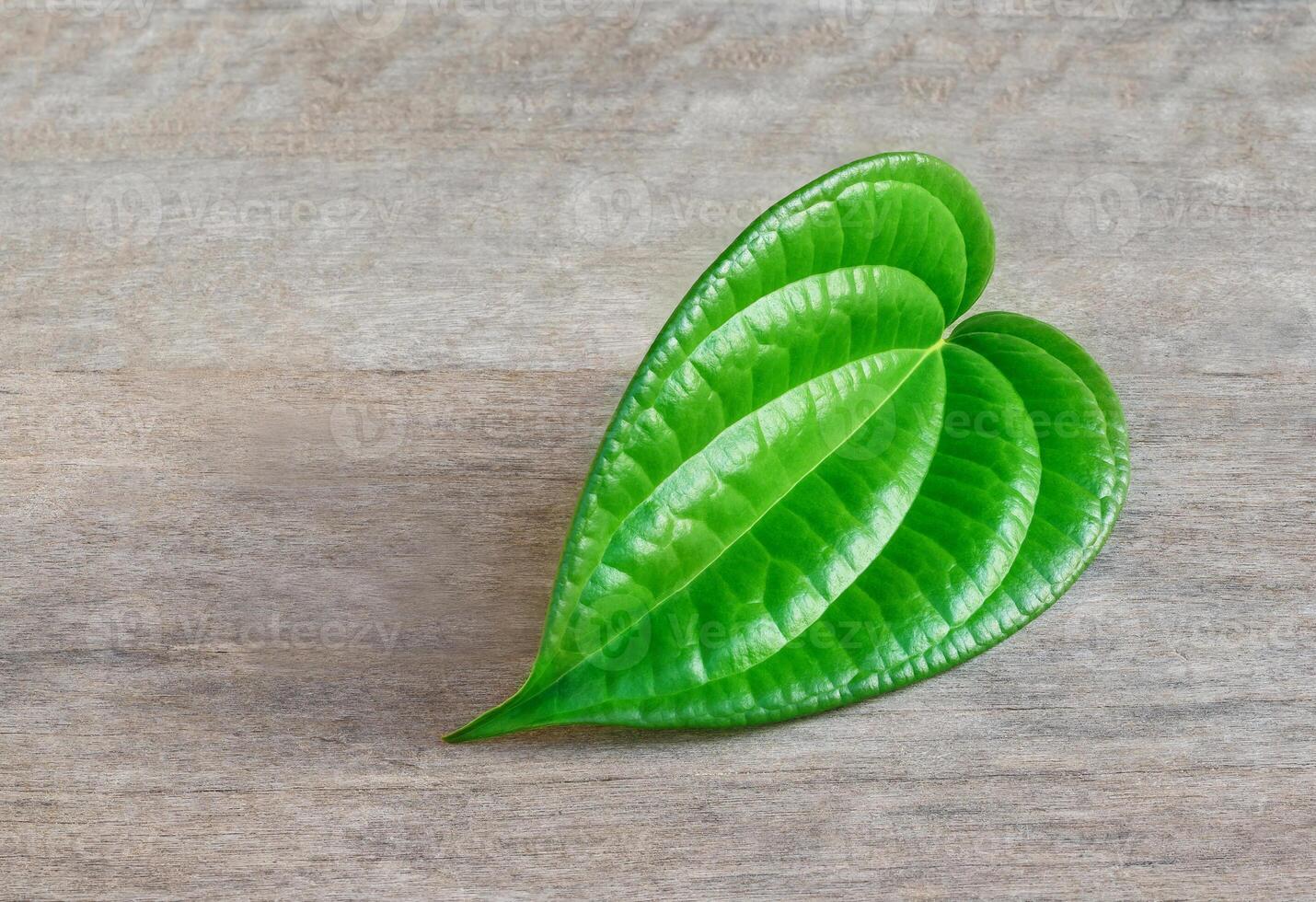 Shaped green betel leaf heart shape on wood photo