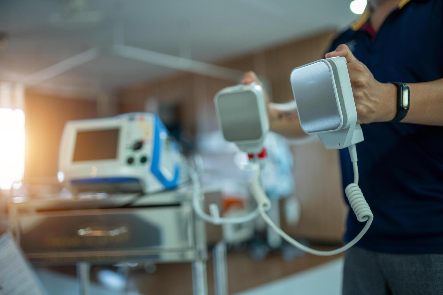 A person is holding a defibrillator in a hospital room photo