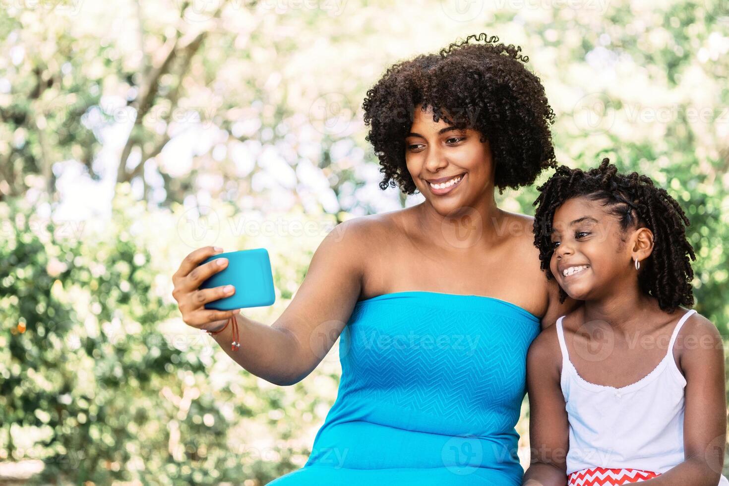 portrait of an afro american woman with a little girl smiling and joyful taking a selfie. photo