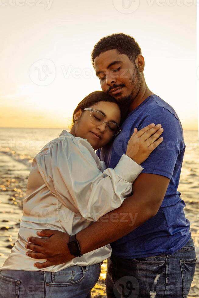 Couple hugging on the beach with beautiful sunset in background. photo