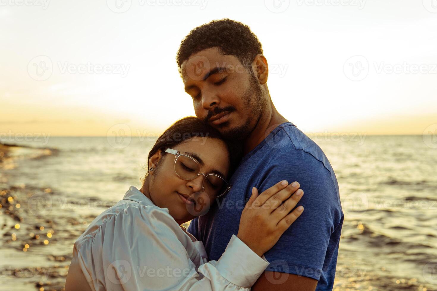 Couple hugging on the beach with beautiful sunset in background. photo