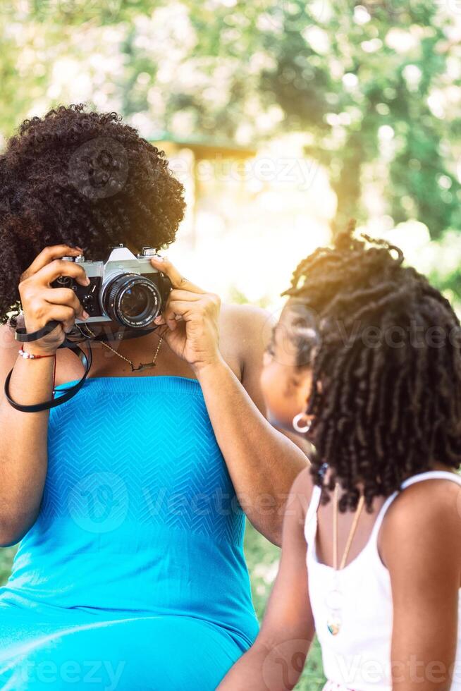 portrait of a woman with afro taking a picture of a little girl. concept photography and learning. photo