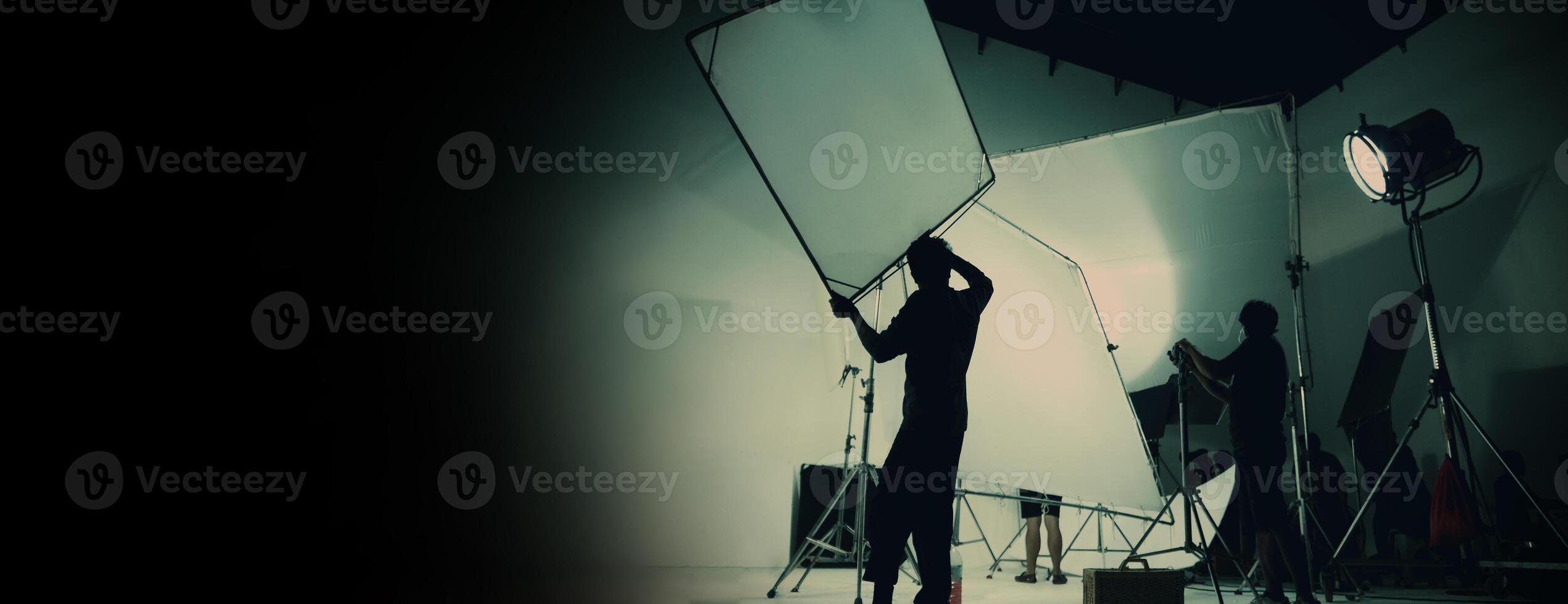 Silhouette of film production behind the scenes or B roll or making of TV commercial movie that film crew team lightman and cameraman working together with director in big studio with pro equipments photo