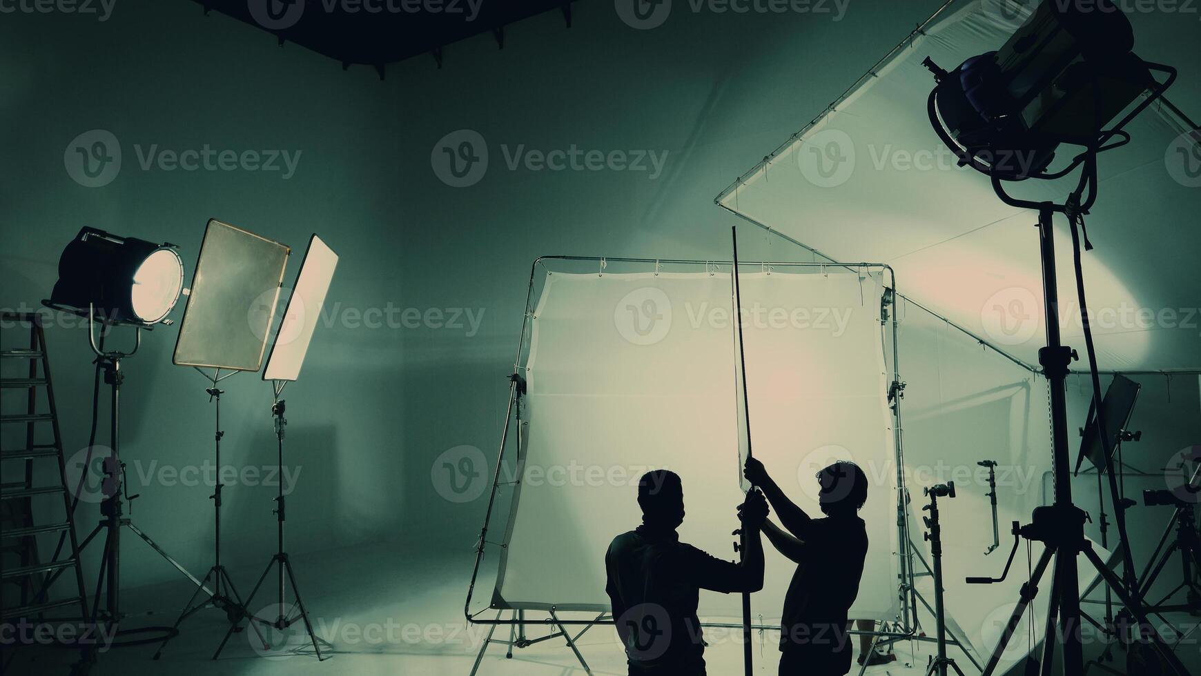 Silhouette of film production behind the scenes or B roll or making of TV commercial movie that film crew team lightman and cameraman working together with director in big studio with pro equipments photo