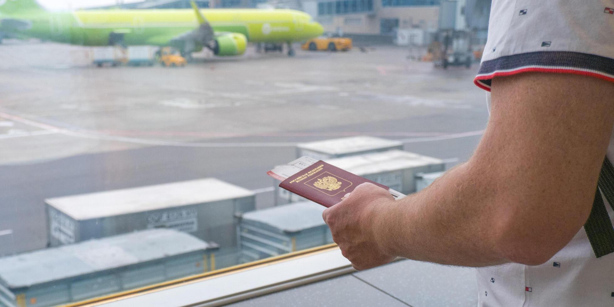 Male hands holding passport with plane tickets, top view photo