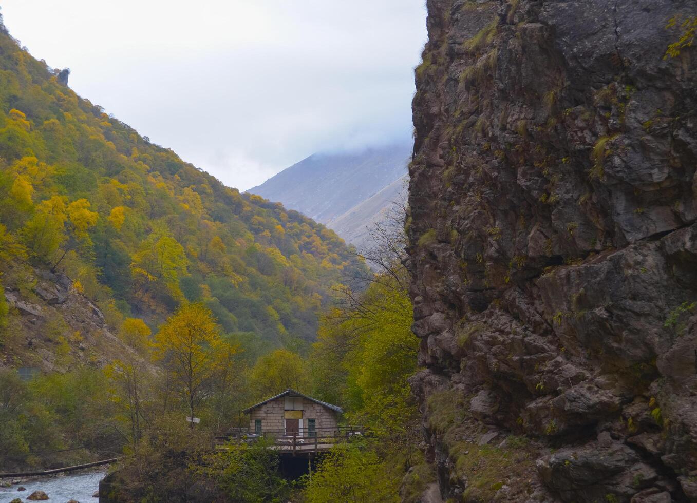A small house near a mountain river and the foot of the misty mountains. North Caucasus, Russia. photo