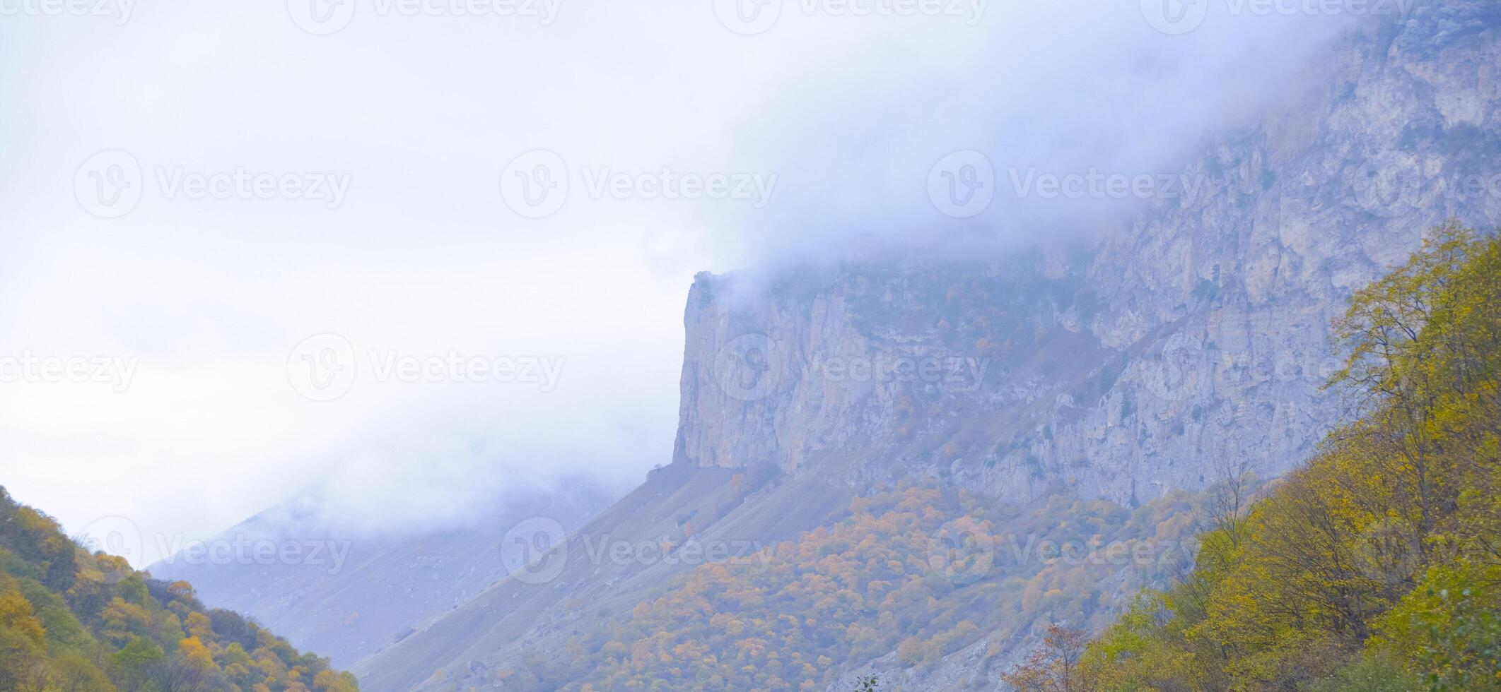 Cloudy foggy sky, mountain peaks covered with fog in the morning. Caucasus Mountains, Russia. photo