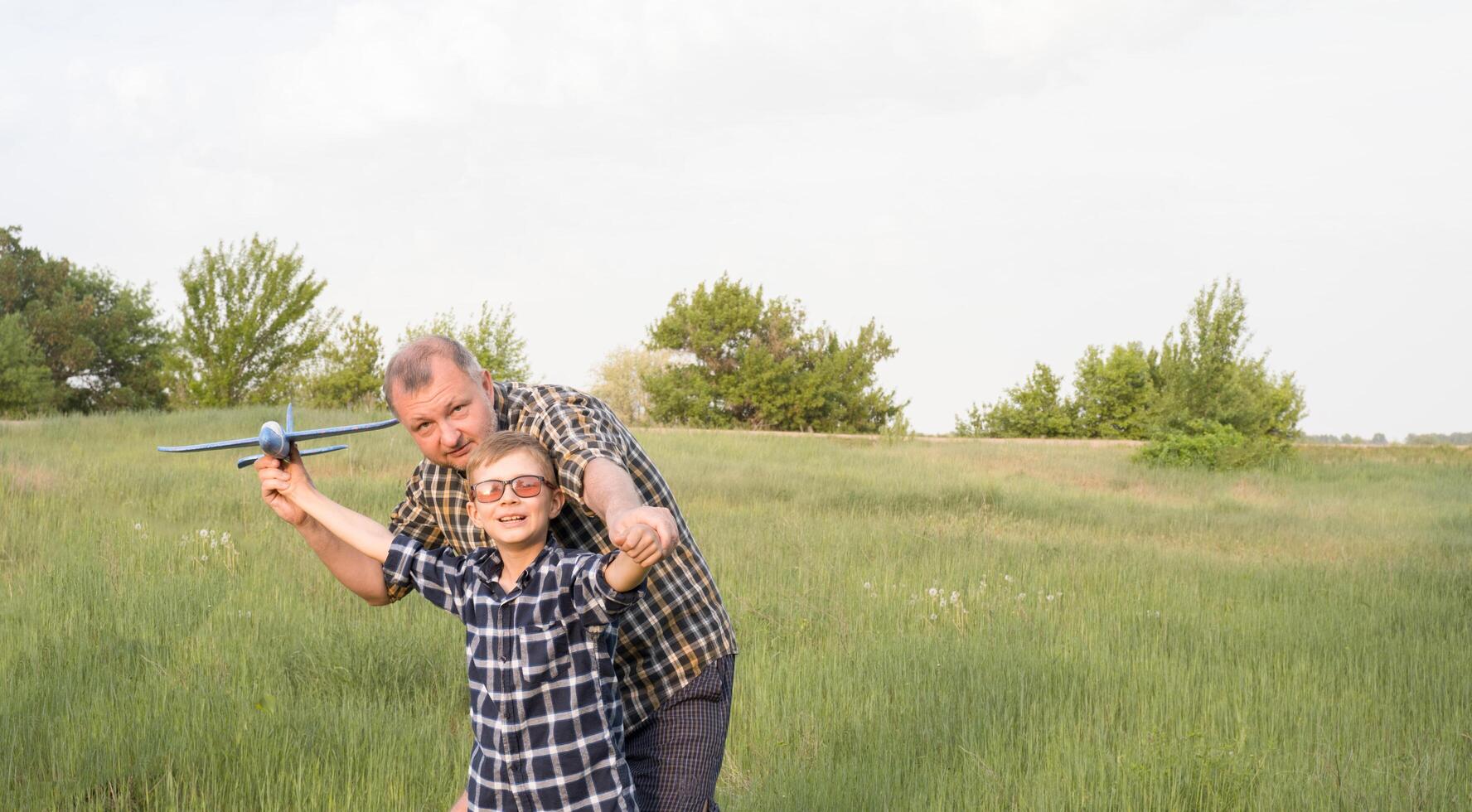 Father and son having fun in the field playing with an airplane photo