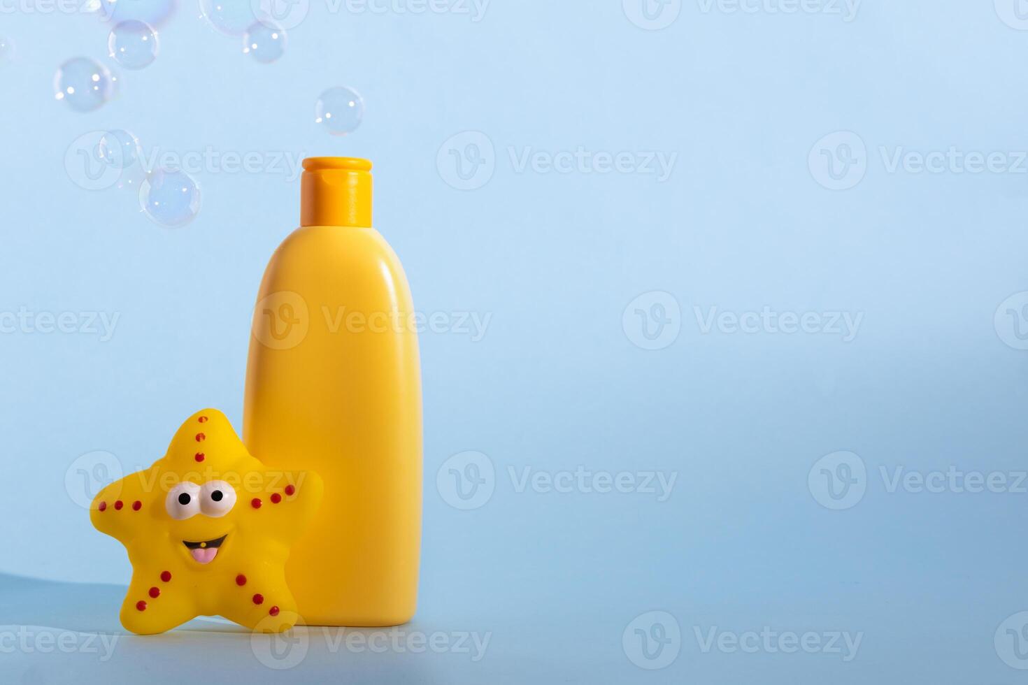 Mockup of a yellow bottle of baby washing gel, bath foam, liquid soap or shampoo with yellow star fish and flying soap bubbles. Kid's hygiene. Template for design. photo