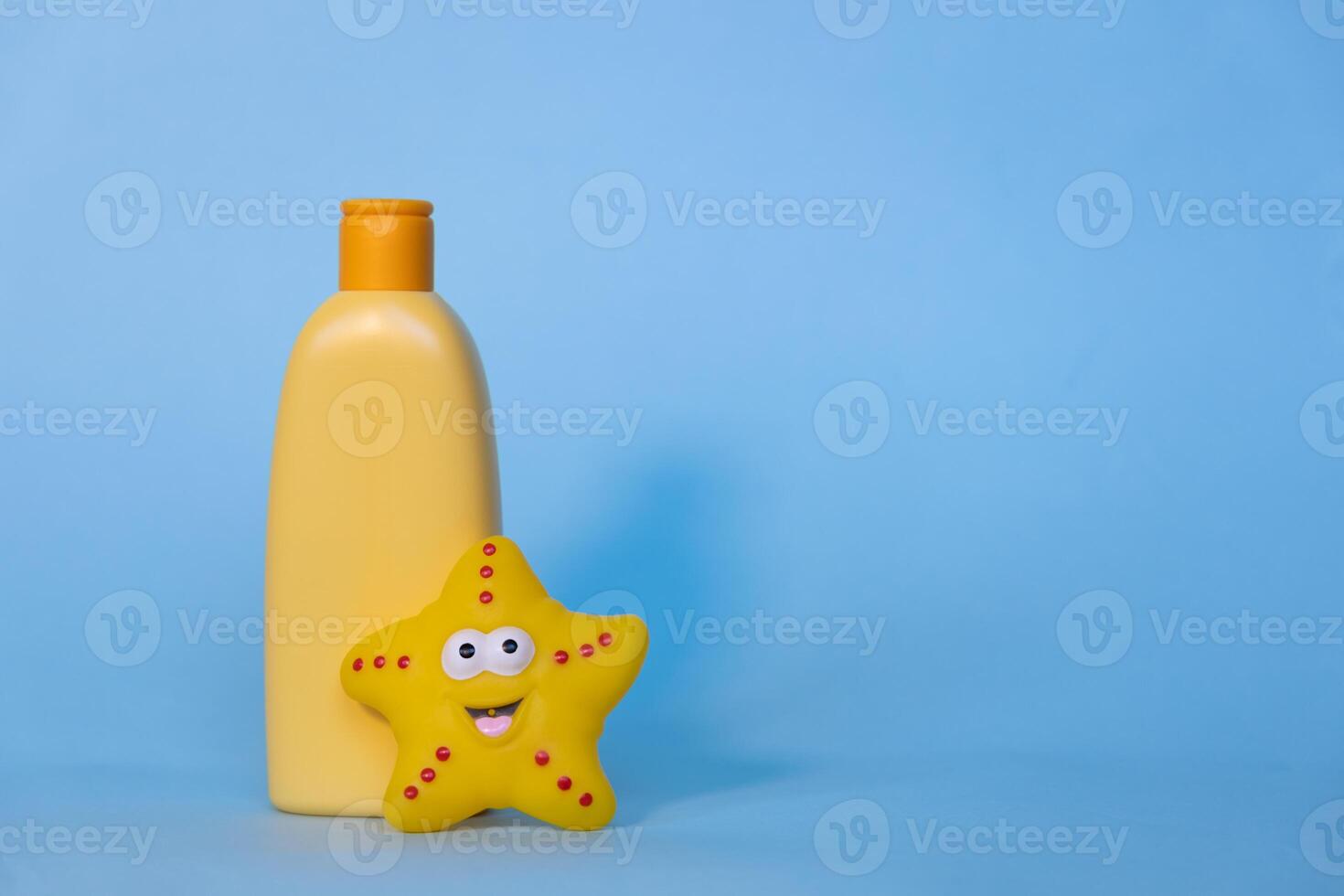 Yellow layout of a children's cosmetic product with a place for a logo and funny toy on a blue background. Baby shampoo, shower gel or body lotion. Space for text photo