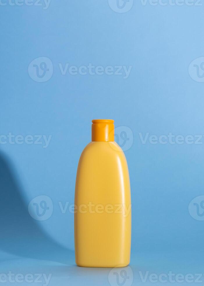 Mock up of a yellow bottle with children's cosmetics on a blue background. Hard shadows, copy space photo